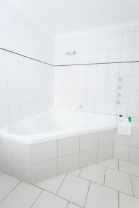 a white bathroom with a tub and a toilet at The Black Bull Motel in Traralgon