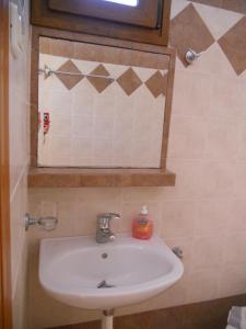 La salle de bains est pourvue d'un lavabo blanc et d'un miroir. dans l'établissement Studios Alexandros, à Sarti