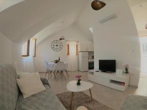 a living room with a couch and a tv and a table at Apartment Vesna in Primošten