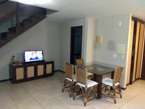 a dining room with a table and chairs and a tv at Solar Pipa Apartamentos in Pipa