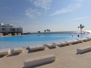 Una piscina con tumbonas blancas y el océano. en ARIA OCEAN ACQUA NUEVO VALLARTA, en Nuevo Vallarta  13 fotos más