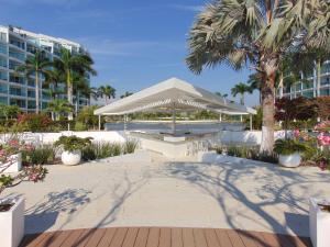 Una mesa de picnic con una sombrilla blanca frente a un edificio. en ARIA OCEAN ACQUA NUEVO VALLARTA, en Nuevo Vallarta 