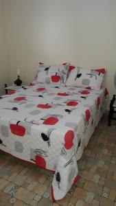 a bed with a red and white comforter with black cats on it at Casa Praia de Arroio do Sal - Balneário São Paulo in Arroio do Sal