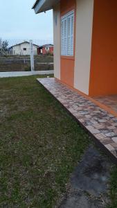 a side of a house with a grass yard at Casa Praia de Arroio do Sal - Balneário São Paulo in Arroio do Sal