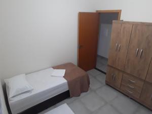 a small bedroom with a bed and a wooden cabinet at RESIDENCIA CIDADE VERDE 2, SINTA-SE EM CASA. in Maringá
