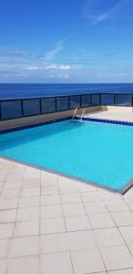 a swimming pool with the ocean in the background at Farol Barra flat 412 in Salvador +26 photos