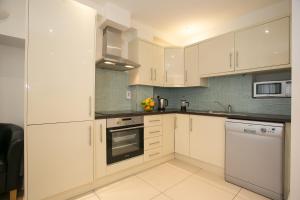 a kitchen with white cabinets and white appliances at Temple Bar District Apartments in Dublin