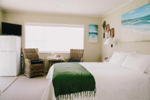 a bedroom with a bed and a large window at Studio on Petley in Tairua
