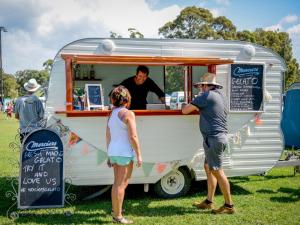 a group of people standing around a food truck at Beachfront Boogaloo in Huskisson