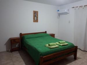 a bedroom with a green bed with two towels on it at Complejo LUMA, Con Pileta in Villa Dolores