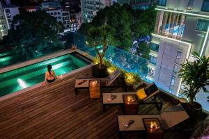 a woman sitting on top of a building with a swimming pool at Au Lac Legend Hotel in Ho Chi Minh City