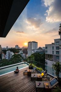 une femme assise sur un balcon avec vue sur une ville dans l'établissement Au Lac Legend Hotel, à Hô-Chi-Minh-Ville