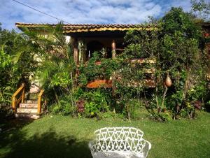 a garden with a white bench in the grass at Jardim das orquídeas in Mucugê