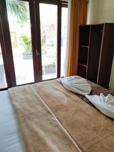 a bed with two pillows on it in front of a window at BBS Homestay in Nusa Lembongan
