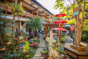 einen Garten mit Pflanzen und Sonnenschirmen in einem Gebäude in der Unterkunft Pao Come Boutique House in Chiang Mai