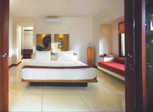 a bedroom with a large white bed and a red couch at Qunci Villas Resort in Senggigi