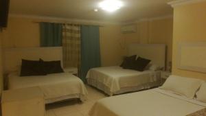 Habitación de hotel con 2 camas y sofá en Suites La Rosa, en Guayaquil