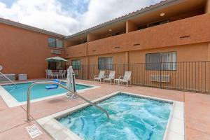 a swimming pool with chairs and a building at Quality Inn & Suites Oceanside Near Camp Pendleton in Oceanside