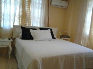 a bedroom with a white bed with black pillows at Suites La Rosa in Guayaquil