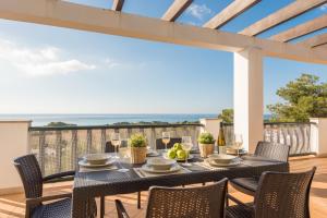a dining table on a deck with a view of the ocean at Villa Sol y Mar in Son Bou