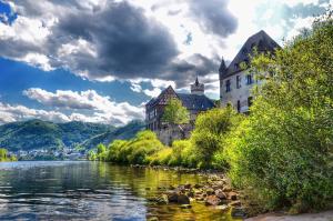 a castle next to a river in front of a building at Hotel Haupt in Kobern-Gondorf