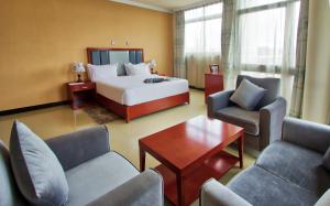 亚的斯亚贝巴Hera Addis Hotel的一间带床、椅子和桌子的酒店房间