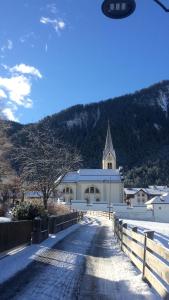 Une grande église blanche avec une cloche dans la neige dans l'établissement Ciasa Cianins, à San Vigilio Di Marebbe
