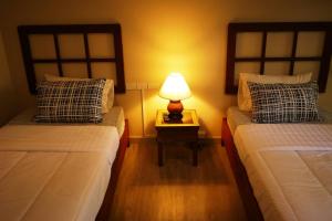 a bedroom with two beds and a lamp on a table at Mountain View GuesthouseChiangmai in Chiang Mai