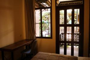 a bedroom with a bed and a desk and a window at Mountain View GuesthouseChiangmai in Chiang Mai