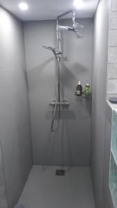 e bagno con doccia su una parete bianca. di Au fil de l'écriture - Appartement sur la Route des Vins à riquewihr a Riquewihr