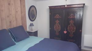 a bedroom with a blue bed and a wooden door at Au fil de l'écriture - Appartement sur la Route des Vins à riquewihr in Riquewihr
