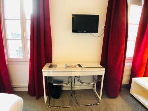 Zimmer mit einem Schreibtisch, einem TV und roten Vorhängen. in der Unterkunft Cit'Hotel Le Volney in Saumur