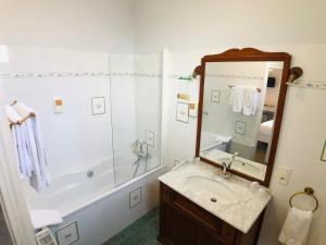 ein Badezimmer mit einer Badewanne, einem Waschbecken und einem Spiegel in der Unterkunft Cit'Hotel Le Volney in Saumur