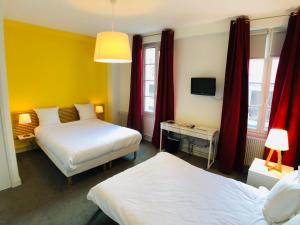 a hotel room with two beds and a television at Cit'Hotel Le Volney in Saumur