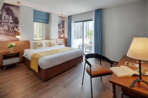ホーチミン・シティにあるリトル サイゴン ブティックホテルのベッド、ランプ付きのデスクが備わるホテルルームです。