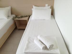 two white beds in a room with towels on them at Zorbas Studios in Lefkos Karpathou