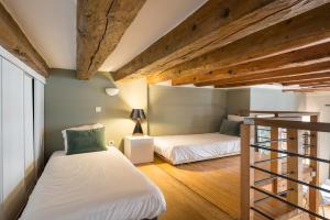 two beds in a small room with wooden ceilings at Honorê - Suites Amboise in Lyon