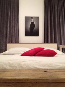 Un dormitorio con una cama con almohadas rojas y una foto en Apartments Kokolo, en Šibenik