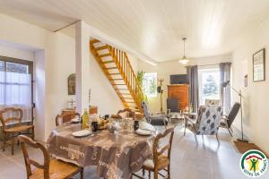 ein Esszimmer mit Tisch und Stühlen und eine Treppe in der Unterkunft Topaze séjour chez le Vigneron in Monnières