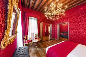 a red bedroom with a bed and a chandelier at Palazzo San Lorenzo in Venice