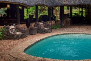 una piscina con sillas y un pabellón en The Royal Sichango Village, en Livingstone