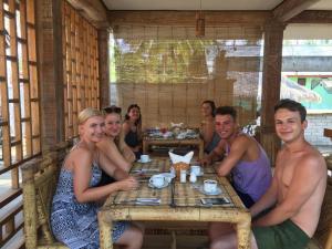 un grupo de personas sentadas en una mesa en un restaurante en Island Beach Bungalow, en Gili Trawangan