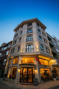 a tall white building with windows on a street at Biga Palas Hotel in Biga