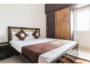 a bedroom with a large bed with a wooden headboard at Olive Serviced Apartments HSR Layout in Bangalore