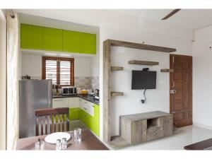 a kitchen with green cabinets and a table in it at Olive Serviced Apartments HSR Layout in Bangalore