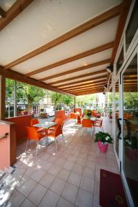a patio with orange chairs and tables on a building at Hotel Sport in Rimini