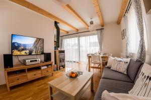 a living room with a couch and a tv at Chata Tatry Resort in Veľká Lomnica