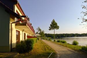 ein Gebäude mit einem Pfad neben einem Wasserkörper in der Unterkunft Seehotel Weit Meer in Waren (Müritz)