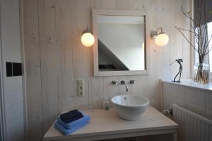 een badkamer met een wastafel en een spiegel bij Zeevanlicht in Hollum