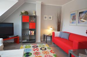 een woonkamer met een rode bank en een tv bij Zeevanlicht in Hollum